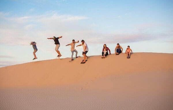 Sandboarding in Agadir: Expansive golden dunes under clear skies.