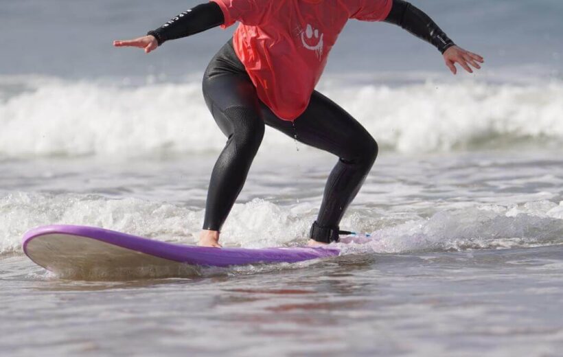 Surfer walking along Agadir beach at sunset with board