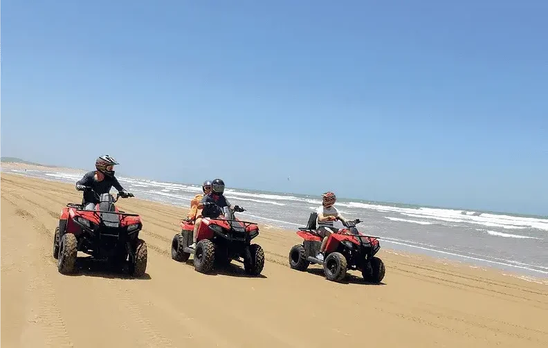 Family riding quad bikes on sand in Tamraght