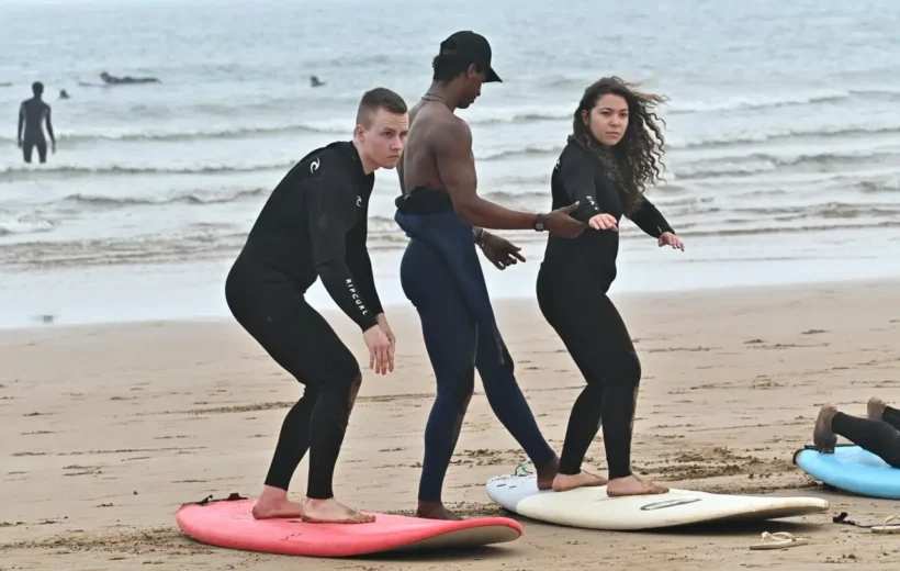 Surf instructor helping a student stand on the surfboard