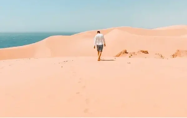 Visitors exploring the desert sand dunes near Agadir, Morocco, enjoying sandboarding and scenic views during a desert adventure.